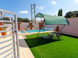 a patio with two chairs and a green umbrella at Unit 5, Capella Place in Accra