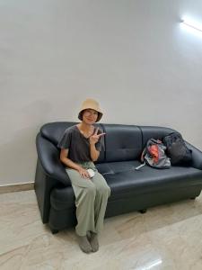 a woman sitting on a couch holding a cell phone at City Central Hostel in Kolkata