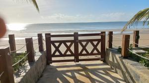 a wooden gate leading to the beach with the ocean at Apartamento Pé na areia em Tamandaré-Porto Cayman in Tamandaré