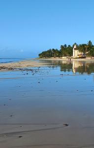 a beach with a house in the middle of the water at Apartamento Pé na areia em Tamandaré-Porto Cayman in Tamandaré