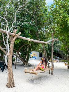 Summer Vibes Beach Front في جزيرة راسدو: امرأة تجلس على مرجيحة على الشاطئ