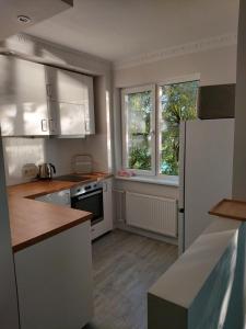 a kitchen with white appliances and two windows at Jauks dzīvoklis ar skaistu skatu uz Daugavu in Riga
