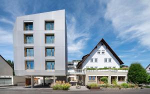biały budynek z brązowym dachem w obiekcie Hotel Maier w mieście Friedrichshafen