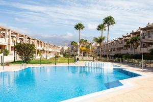 a swimming pool with palm trees and buildings at Apartamento Sotavento I (RM) in El Médano