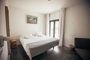 a bedroom with a white bed and a window at MUTE Hostel Porto Covo in Porto Covo
