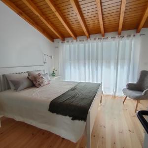a bedroom with a large bed and a chair at Casa d´ Avó Glória in Alvoco das Várzeas