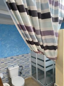 baño con aseo y cortina de ducha a rayas en BLANCA FRENTE AL MAR, en Punta Mujeres 29 fotos más