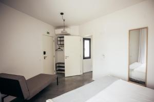 a white bedroom with a bed and a chair at MUTE Hostel Porto Covo in Porto Covo