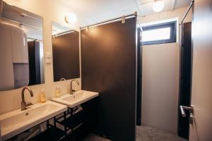 a bathroom with a sink and a shower with a mirror at MUTE Hostel Porto Covo in Porto Covo