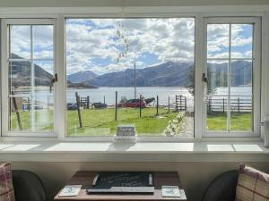 a window with a view of a lake and mountains at Cuillin Cottage in Arnisdale