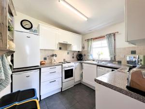 a kitchen with white cabinets and white appliances at Cuillin Cottage in Arnisdale