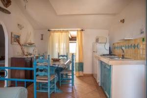 een keuken met blauwe stoelen, een tafel en een koelkast bij Casa Gallo in Marinella
