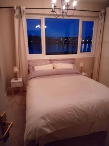 a bedroom with a large white bed with a window at The Retreat, a Luxury Riverside Cottage & garden in Southampton