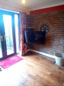 a living room with a tv and a brick wall at The Retreat, a Luxury Riverside Cottage & garden in Southampton