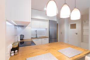 ビャウィストクにあるApartment Royal VIII - Łąkowa 1のキッチン(木製テーブル、白いキャビネット付)