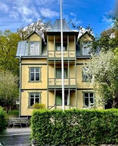 a yellow house with a porch and a balcony at Historic apartment near the city by the water in Solna