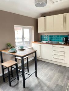 eine Küche mit weißen Schränken, einem Tisch und einem Waschbecken in der Unterkunft Annex - Garden View in Bristol