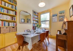 West Hill Cottage في برايتون أند هوف: غرفة طعام مع طاولة وكراسي ورفوف كتب
