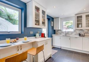 West Hill Cottage في برايتون أند هوف: مطبخ به دواليب بيضاء وجدران زرقاء