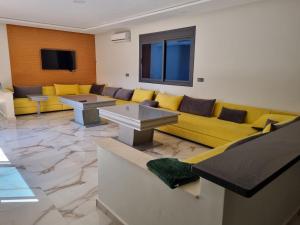 a waiting room with a yellow couch and tables at Villa Berkania piscine privée - 8 pers in Berkane