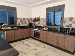 a kitchen with wooden cabinets and a microwave and windows at Villa Berkania piscine privée - 8 pers in Berkawe