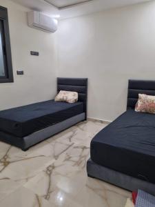 two beds sitting in a room with marble floors at Villa Berkania piscine privée - 8 pers in Berkane