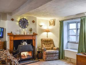 a living room with a fireplace and a chair and a clock at Hoopers Farmhouse in Tilshead