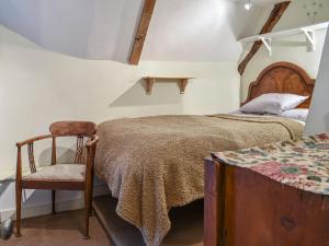 a bedroom with a bed and a chair at Hoopers Farmhouse in Tilshead