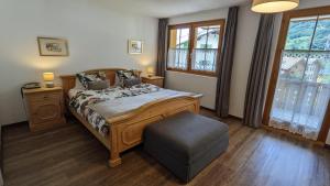 a bedroom with a bed and a chair and windows at Hotel Beau-Séjour in Leukerbad