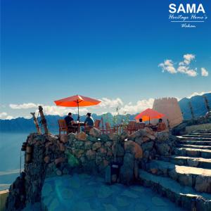 SAMA Wakan Heritage Homes في Fanjah: مجموعة من الناس يجلسون على طاولة مع مظلات