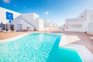 a swimming pool in front of a white building at Apartamentos Tabaiba in Costa Teguise