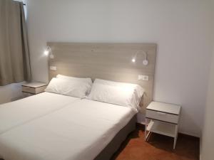 sypialnia z dużym białym łóżkiem i stolikiem nocnym w obiekcie Apartamentos Tabaiba w Costa Teguise