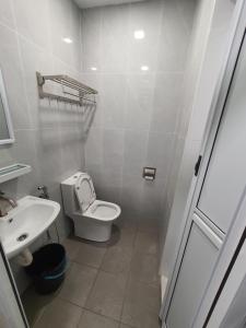 a white bathroom with a toilet and a sink at Voon 2 bedroom homestay in Mersing