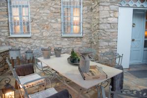 a white table with chairs and a stone wall at Dandy Villas Nymfaio - Snow Fairy - Sauna in Nymfaio