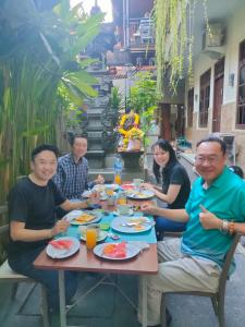 Eine Gruppe von Menschen, die an einem Tisch sitzen und Essen essen. in der Unterkunft Asta House in Kuta