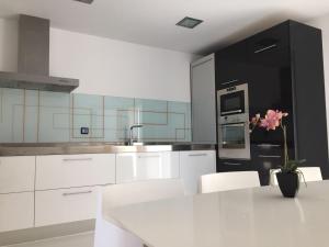 a kitchen with white cabinets and a table with a vase of flowers at Casa BlancadeNavarra in Fitero