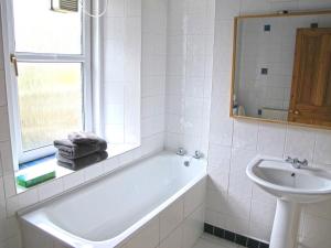 a white bathroom with a tub and a sink at House by the Harbour - NC500 Route in Wick