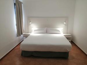 sypialnia z łóżkiem z białymi prześcieradłami i poduszkami w obiekcie Apartamentos Tabaiba w Costa Teguise