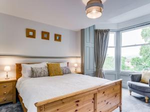 a bedroom with a bed and a chair and a window at Gorgeous cottage in Bowness in Bowness-on-Windermere