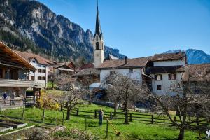 uma mulher parada num campo em frente a uma aldeia com uma igreja em Landhus Almens em Almens