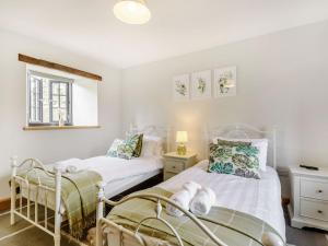 two twin beds in a room with white walls at Penshenkin Barn in Llanfihangel-nant-Melan