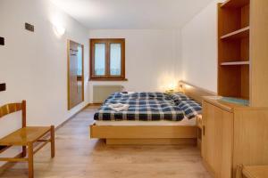 ein Schlafzimmer mit einem Bett und einem Stuhl darin in der Unterkunft Appartamenti Vittoria Bilo in Valfurva