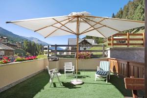 eine Terrasse mit 2 Stühlen und einem Sonnenschirm auf dem Balkon in der Unterkunft Appartamenti Vittoria Bilo in Valfurva
