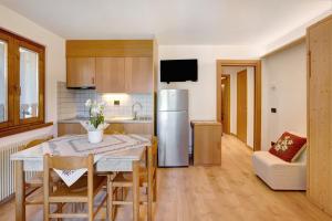 eine Küche und ein Esszimmer mit einem Tisch und einem Kühlschrank in der Unterkunft Appartamenti Vittoria Bilo in Valfurva
