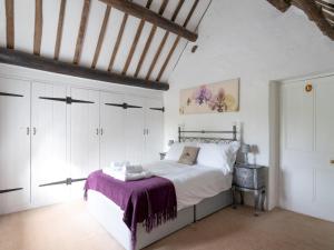a bedroom with white cabinets and a bed with a purple blanket at Pass the Keys Delightful 4 bedroom Cotswold character cottage in Cheltenham