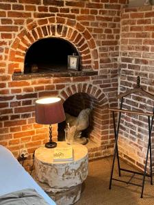 d'un four en briques avec une table et une lampe. dans l'établissement Chambres d'Aumont, à Aumont