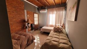 1 dormitorio con 2 camas y pared de ladrillo en departamento confortable en Luján de Cuyo