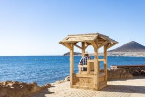 a man sitting in a gazebo by the water at 121 MEDANO Perfect Stay By Sunkeyrents in El Médano