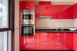 a red kitchen with red cabinets and a microwave at 121 MEDANO Perfect Stay By Sunkeyrents in El Médano