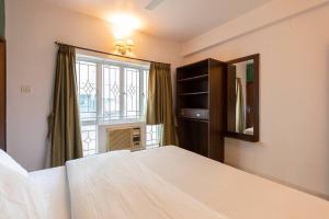 een slaapkamer met een groot bed en een raam bij HANDMADE HOMES HAZRA: 2 BED APARTMENT AT KALIGHAT in Calcutta
